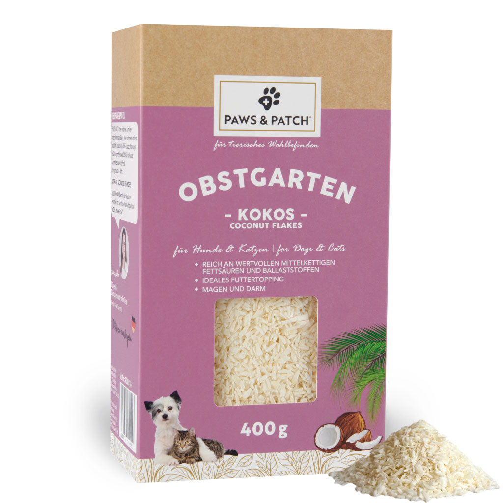 Verpackung aus Pappe in Altrosa mit Sichtfenster, das feine Kokosflocken zeigt - davor ein Häufchen ausgepackte Kokosflocken